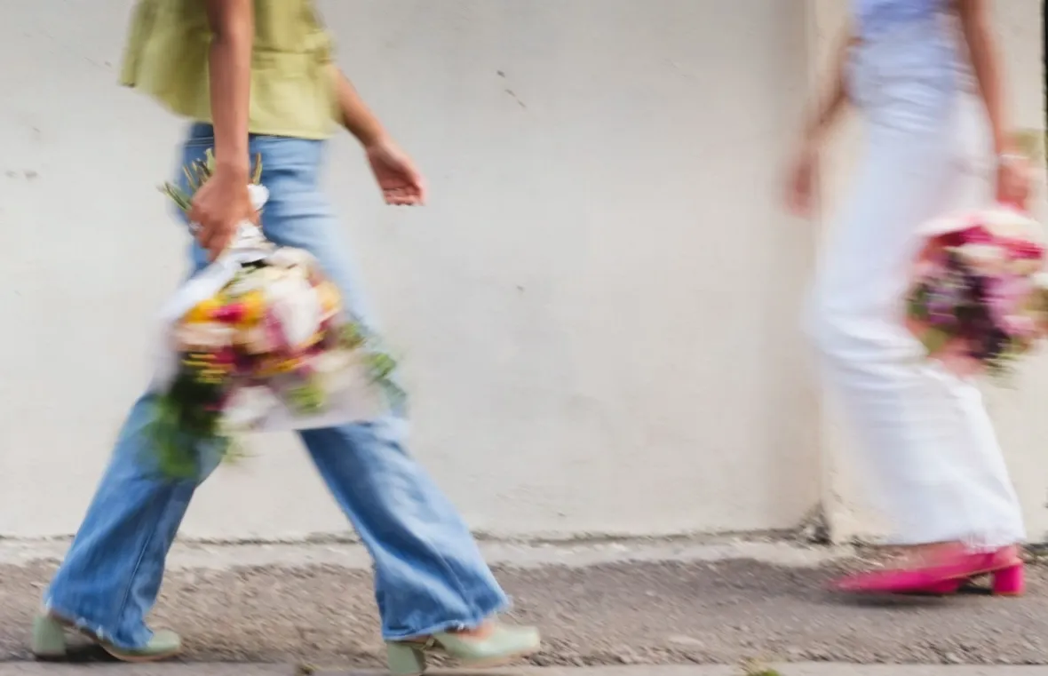 Une passante longeant un mur d'Antananarivo, un bouquet Taxi Amore a la main